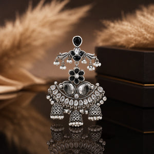 Black pearl-style chandelier earrings on a dark jewellery studio display