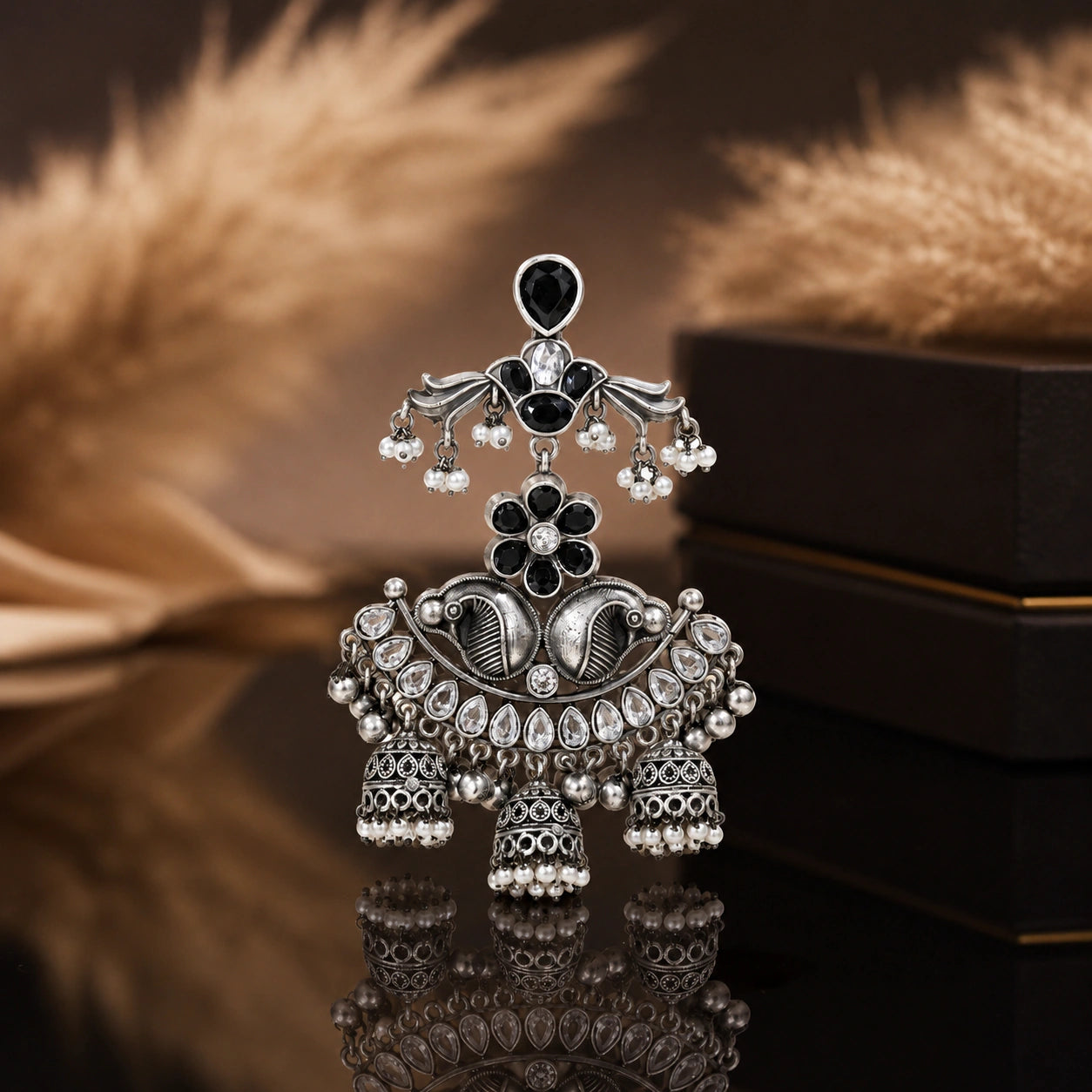 Black pearl-style chandelier earrings on a dark jewellery studio display