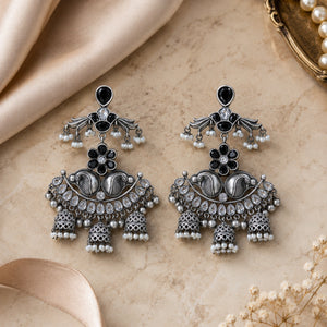 Black pearl-style chandelier earrings styled in an elegant jewellery flat lay