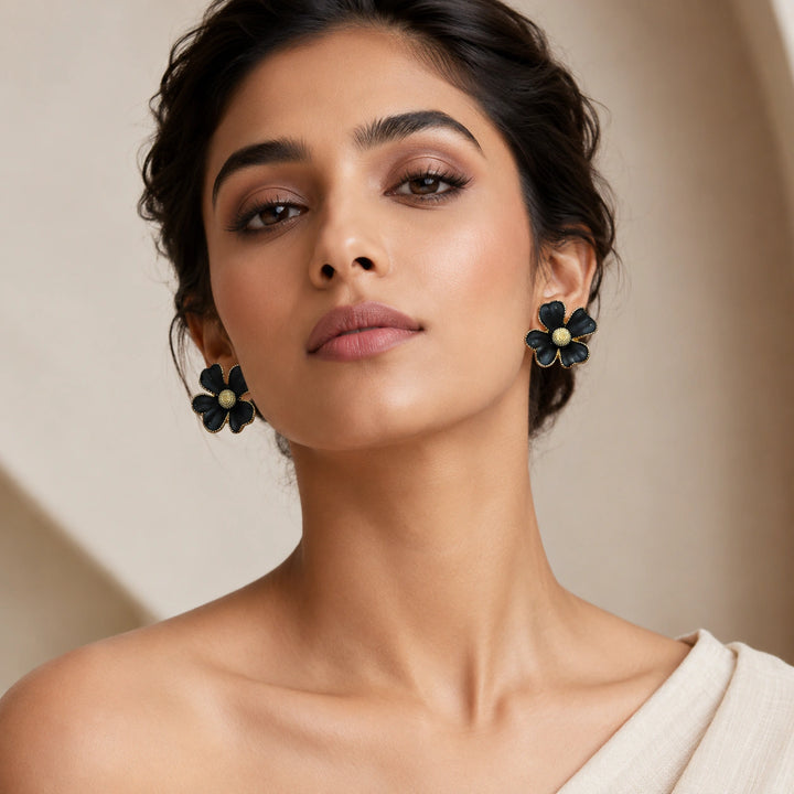 Black gold floral statement earrings on a dark jewellery studio display