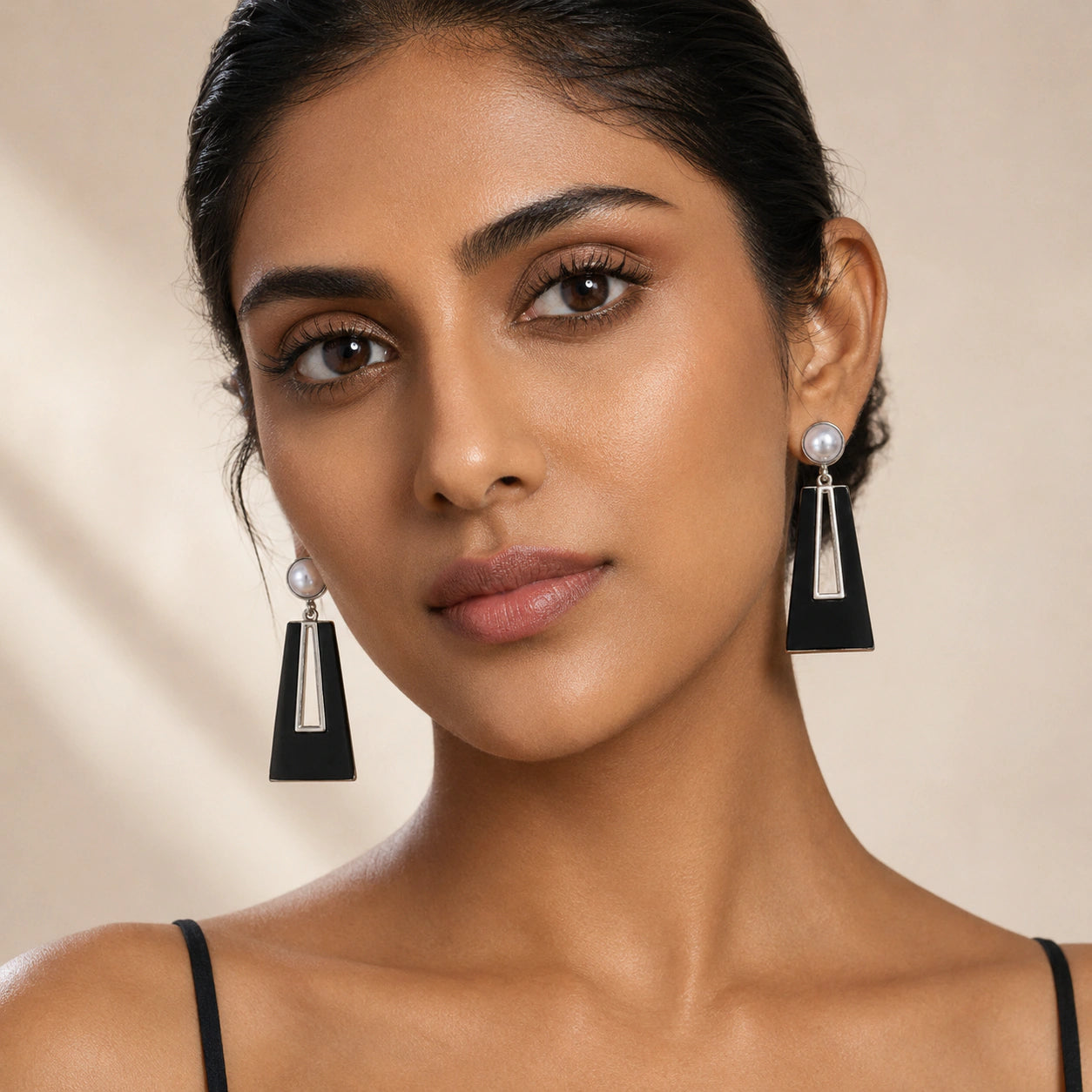 Black pearl geometric earrings on a dark jewellery studio display