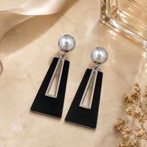 Black pearl geometric earrings styled in a modern jewellery flat lay