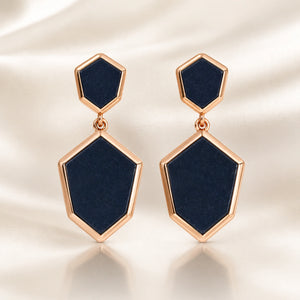 Black rose-gold geometric earrings on a dark jewellery studio display