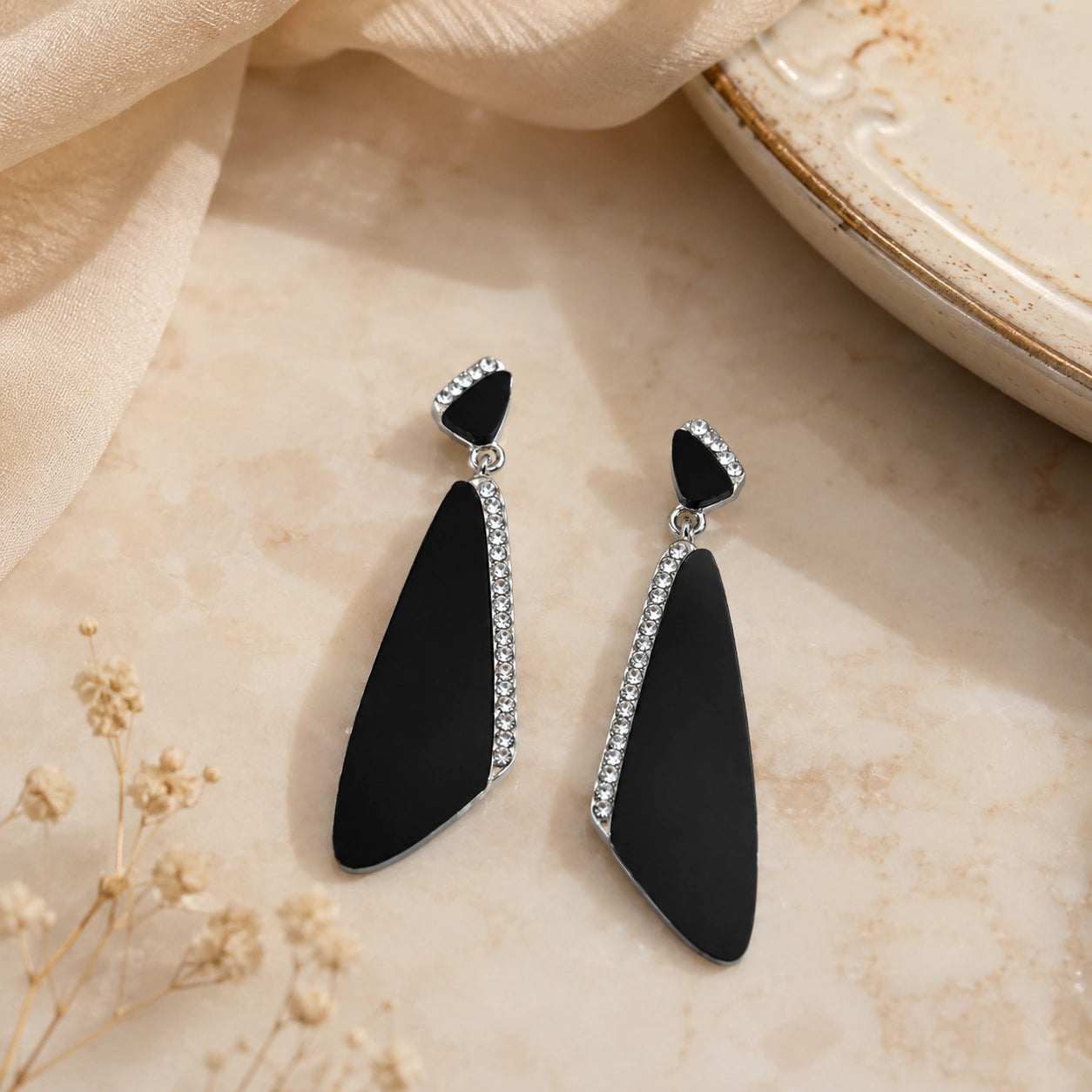 Black silver geometric earrings styled in a modern jewellery flat lay