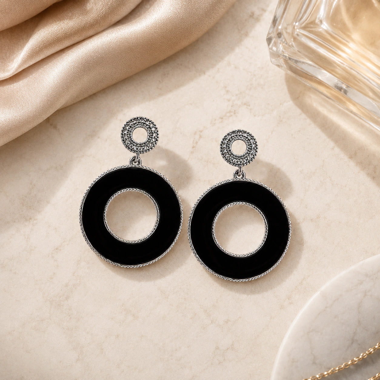Black silver open-centre hoops styled in a modern jewellery flat lay