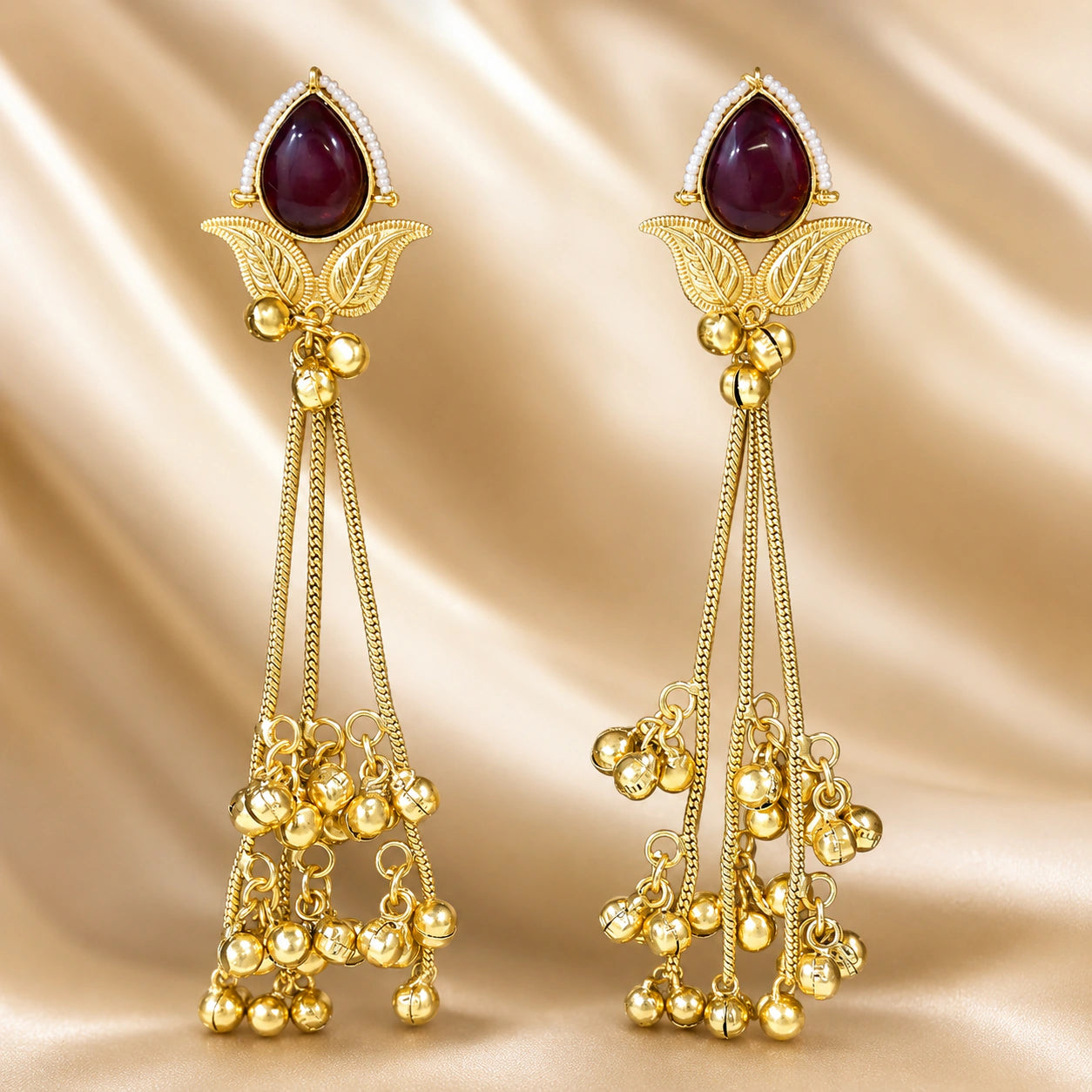 Close-up of maroon Kundan-style stones, pearls and brass-gold chandelier detailing