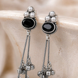 Angled view of German silver black pearl-style jhumka dangle earrings