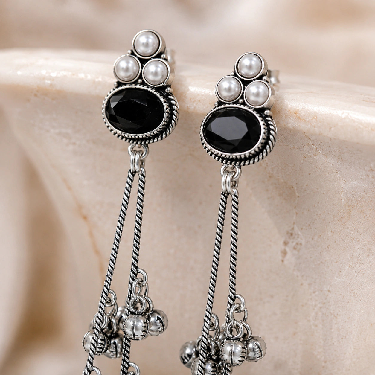 Angled view of German silver black pearl-style jhumka dangle earrings
