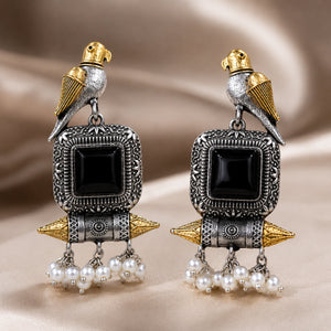 Angled view of German silver black-stone bird pearl-style earrings