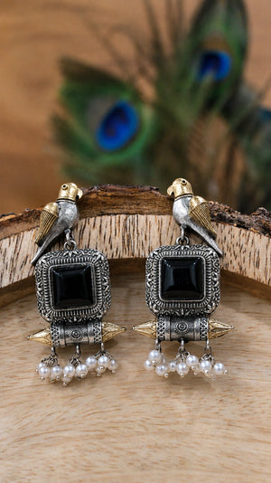 Close-up ear view showing black stones, bird motifs and pearl-style drops