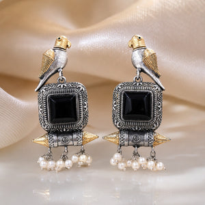 Close-up of black stones, bird motifs and pearl-style dangle detailing