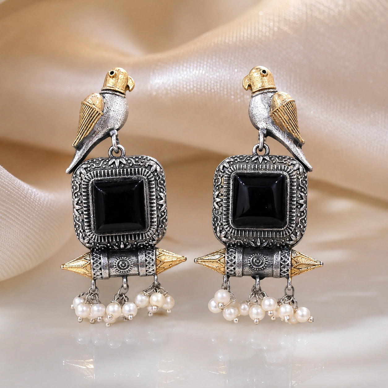 Close-up of black stones, bird motifs and pearl-style dangle detailing