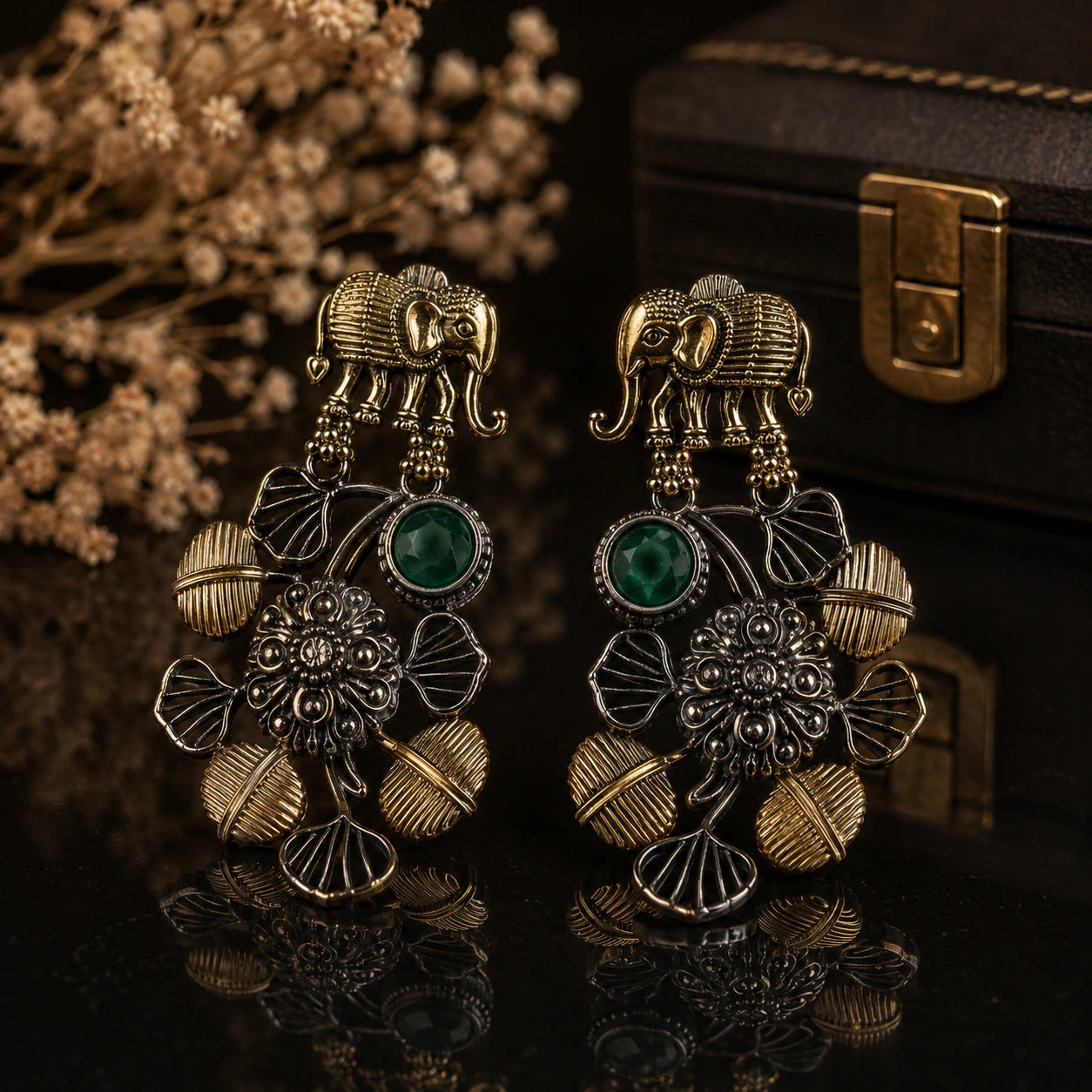 Elephant green-stone chandelier earrings on a dark jewellery studio display