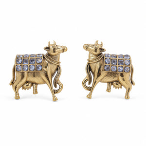 Angled view of German silver gold cow-motif crystal drop earrings