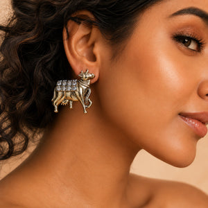 Close-up of gold-tone cow motifs and crystal-style drop detailing