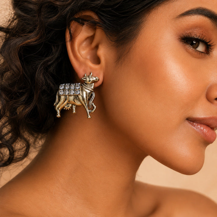 Close-up of gold-tone cow motifs and crystal-style drop detailing