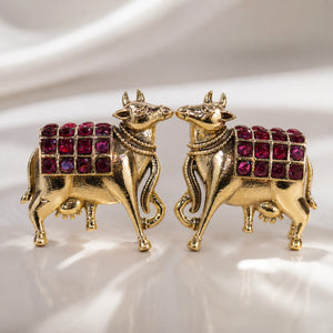 Angled view of German silver gold-tone maroon cow-motif earrings