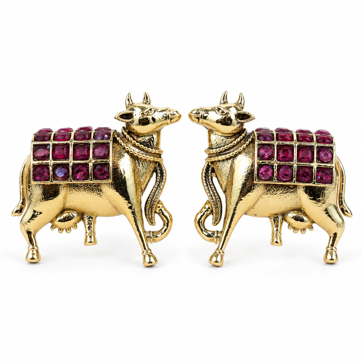 Gold maroon cow-motif dangle earrings on a dark jewellery studio display