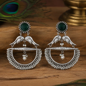 Angled view of German silver green bird pearl chandelier earrings