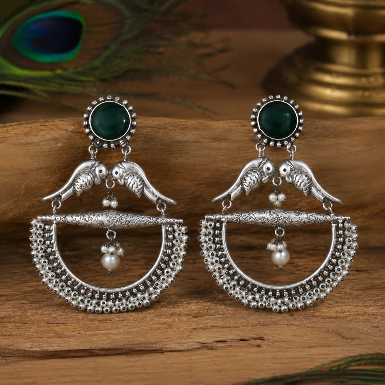 Angled view of German silver green bird pearl chandelier earrings