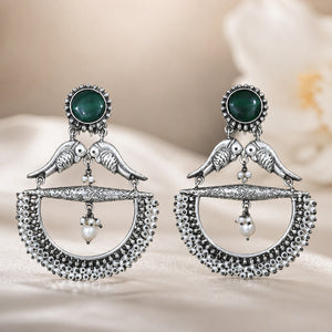 Green bird pearl chandelier earrings on a dark jewellery studio display