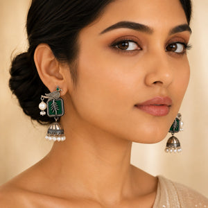 Angled view of German silver green bird-motif pearl jhumka earrings
