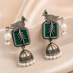 Green bird-motif pearl jhumka earrings styled in a jewellery flat lay