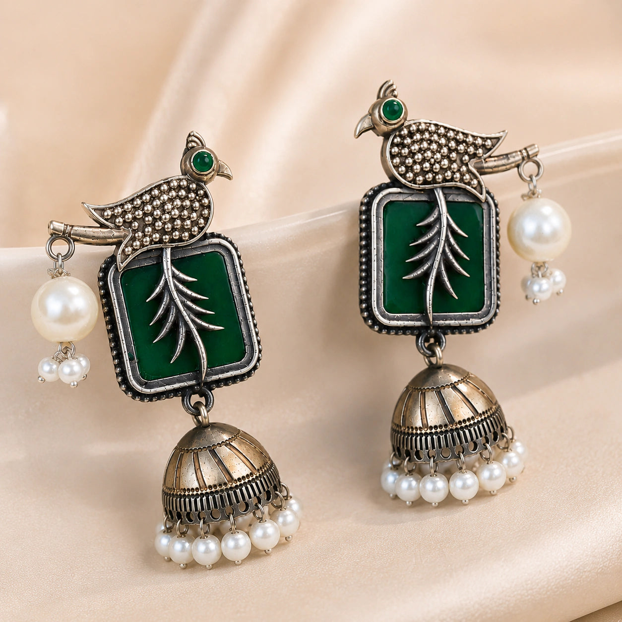 Green bird-motif pearl jhumka earrings styled in a jewellery flat lay