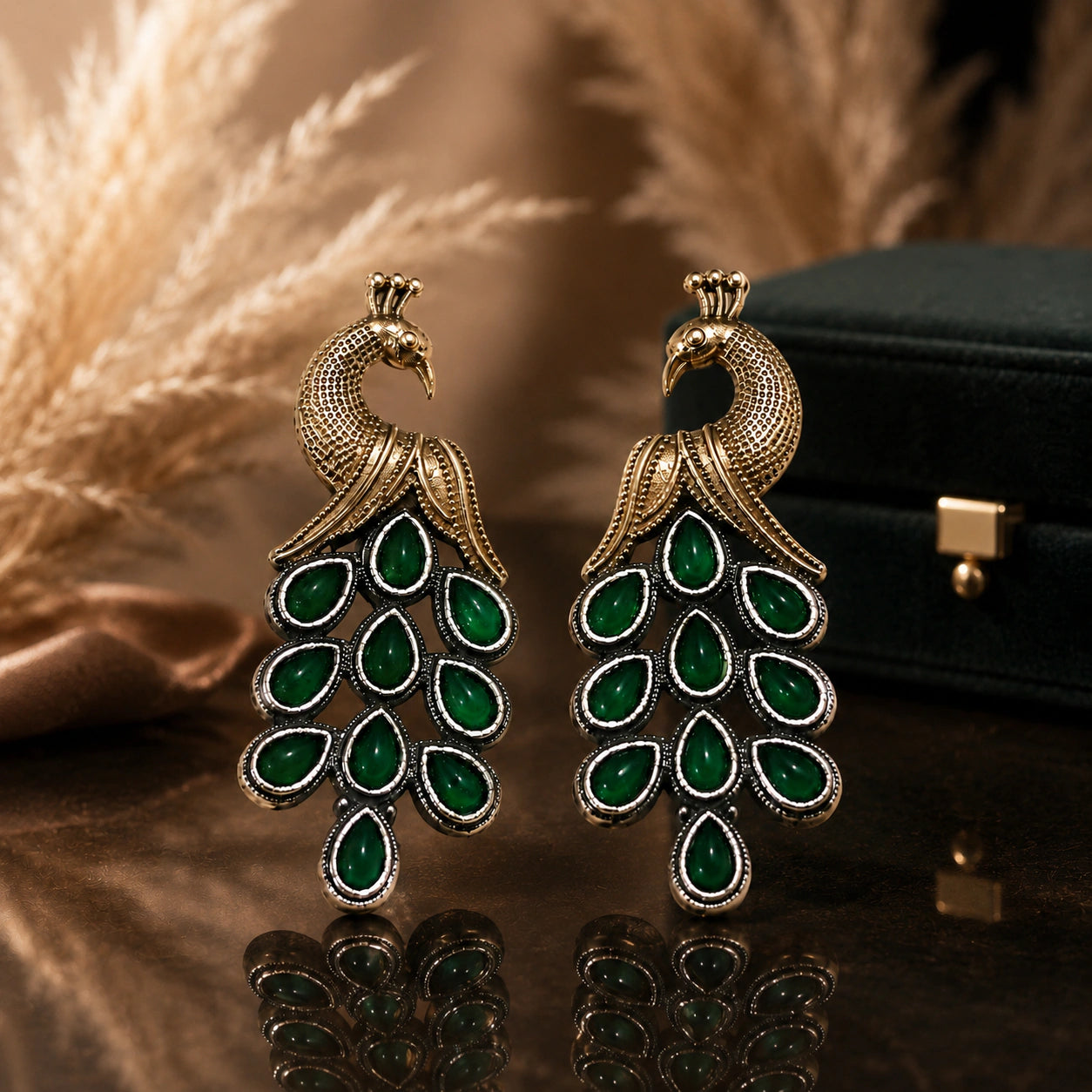 Green peacock chandelier earrings on a glossy dark reflective jewellery display