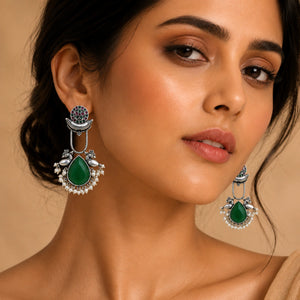 Angled view of German silver green pearl-style bird-motif earrings