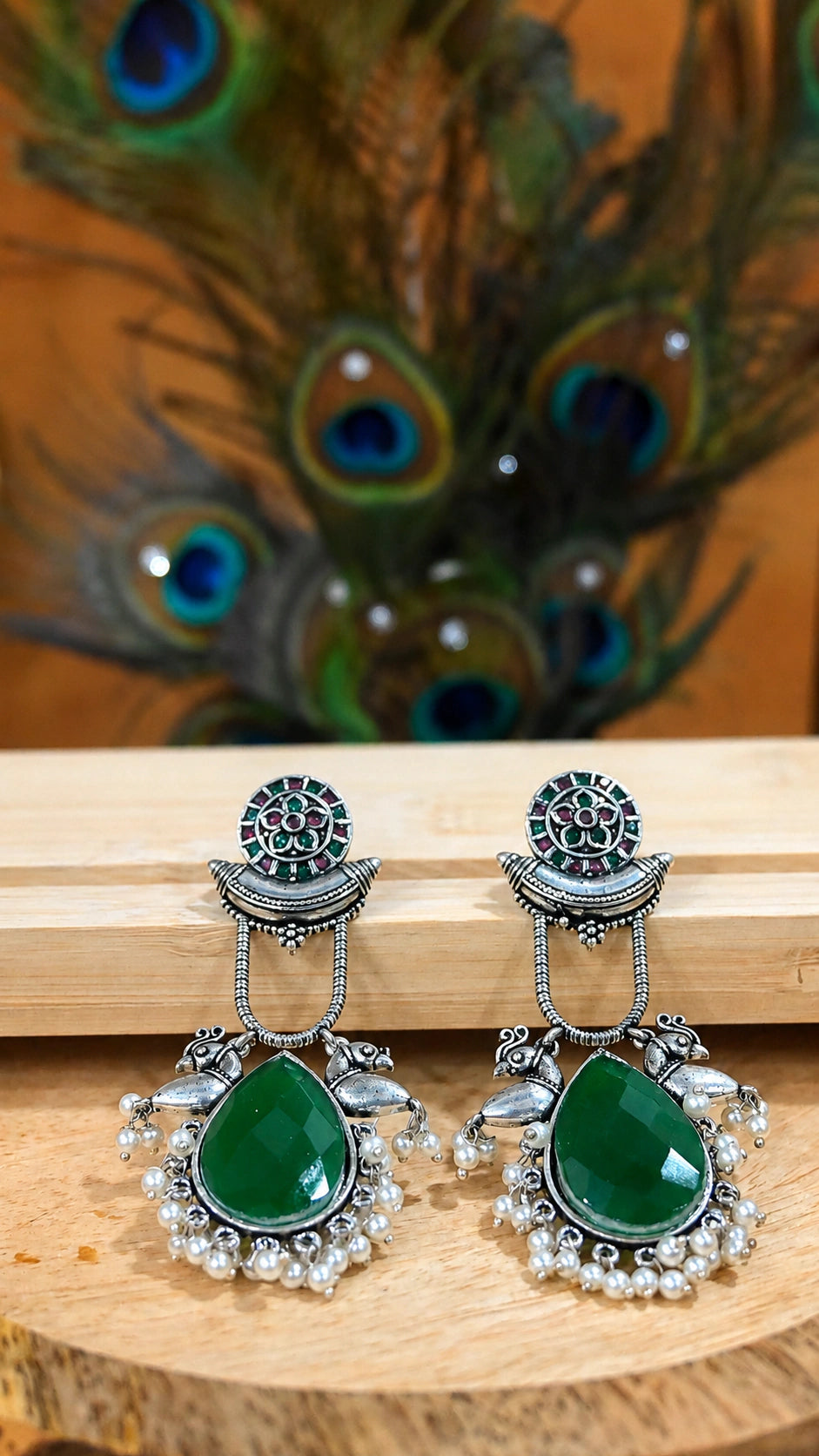 Close-up ear view showing green accents, bird motifs and pearl-style drops