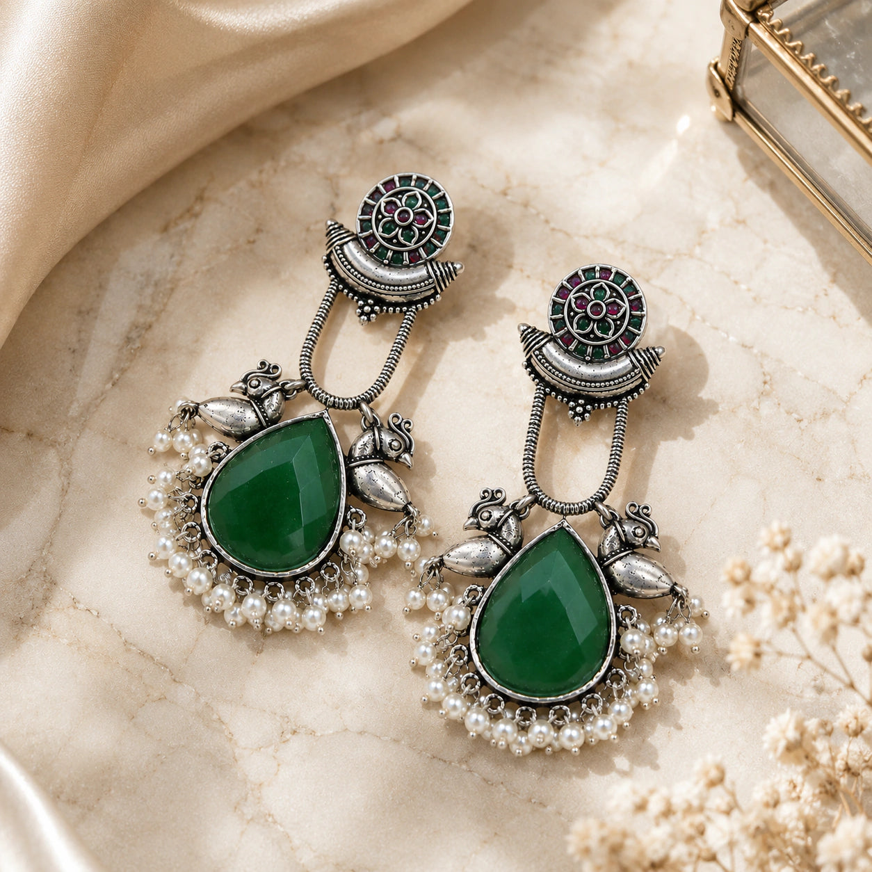 Green pearl bird-motif earrings styled in an elegant jewellery flat lay