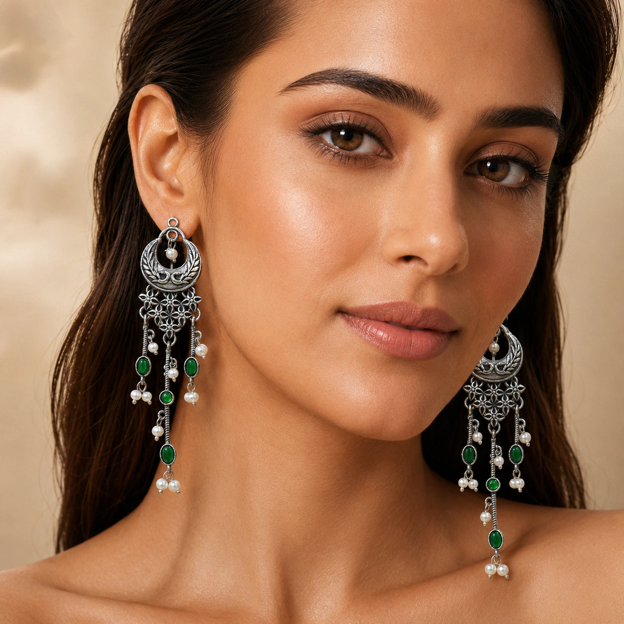 Green pearl-style chandelier earrings on a dark jewellery studio display