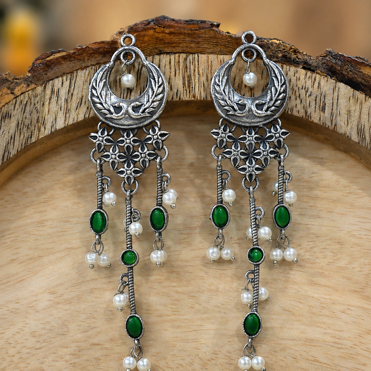 Green pearl-style chandelier earrings styled in an elegant jewellery flat lay