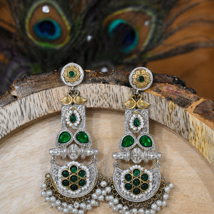 Green pearl peacock chandelier earrings on a dark jewellery studio display