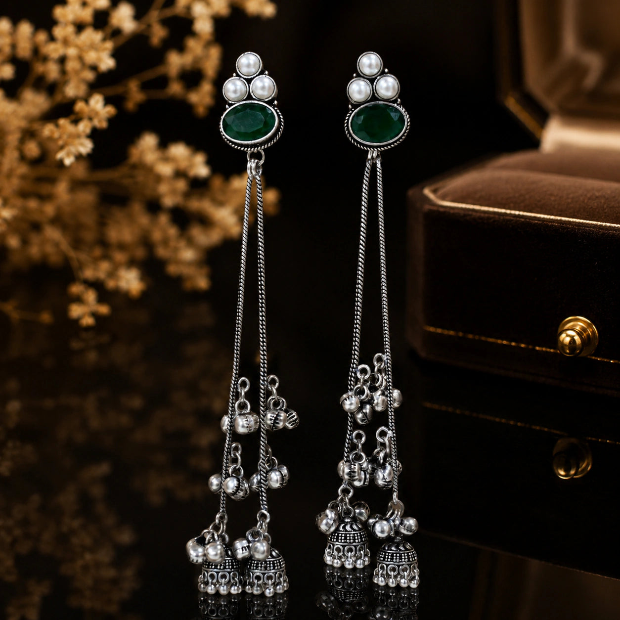 Green pearl tassel dangle earrings on a glossy dark jewellery display