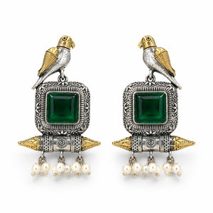Angled view of German silver green-stone bird pearl dangle earrings