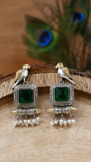 Close-up ear view showing green stones, bird motifs and pearl-style drops
