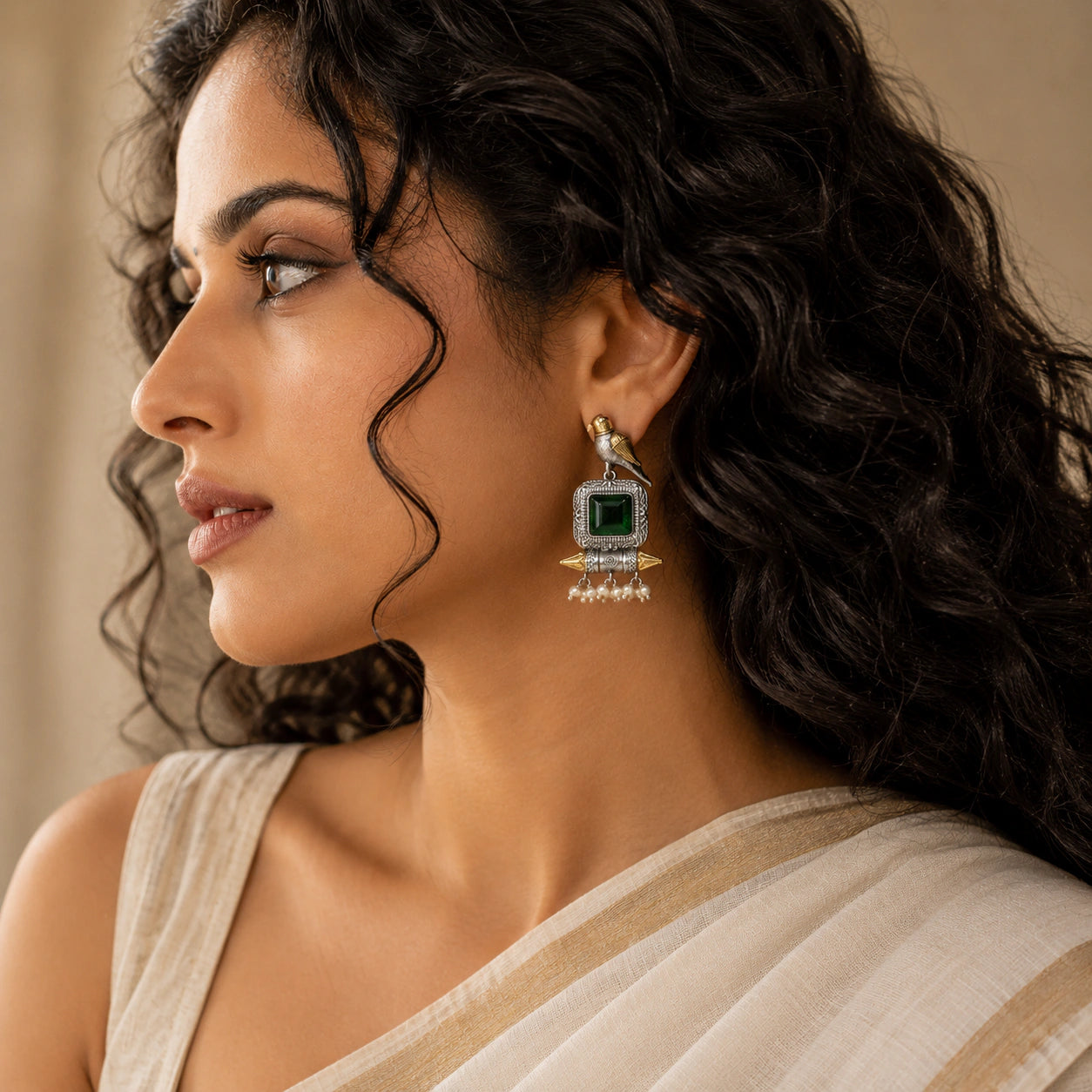 Close-up of green stones, bird motifs and pearl-style dangle detailing