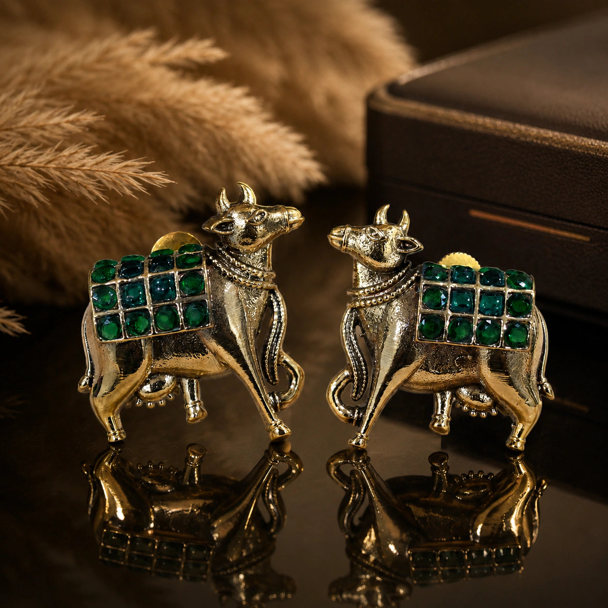 Green-stone cow-motif earrings on a dark jewellery studio display