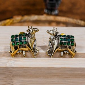 Green-stone cow-motif earrings styled in an elegant jewellery flat lay