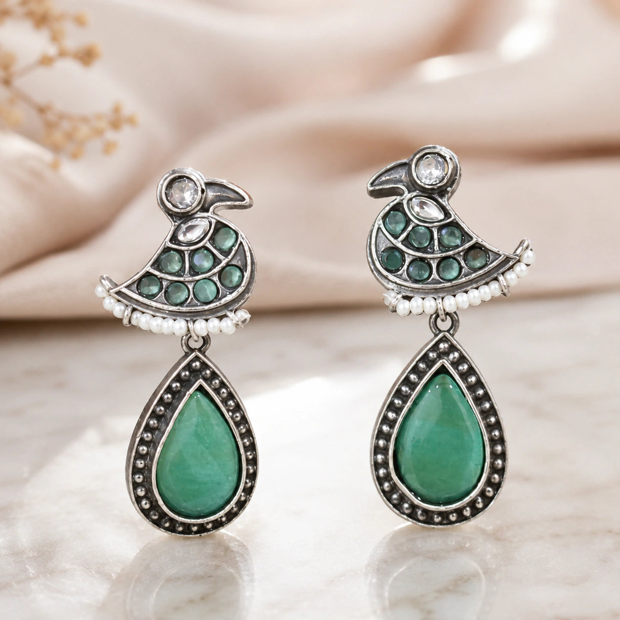 Angled view of German silver green-stone pearl-style dangle earrings