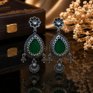 Green teardrop beaded earrings on a dark jewellery studio display