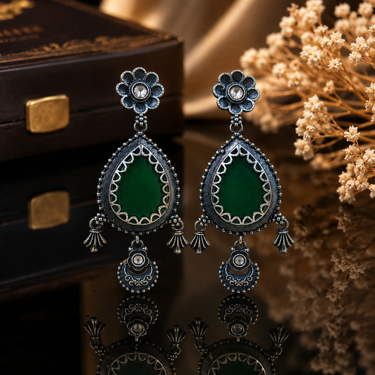 Green teardrop beaded earrings on a dark jewellery studio display