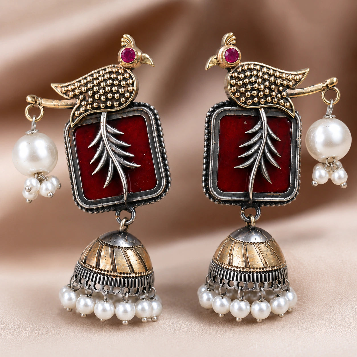 Maroon bird pearl jhumka earrings styled in an elegant jewellery flat lay