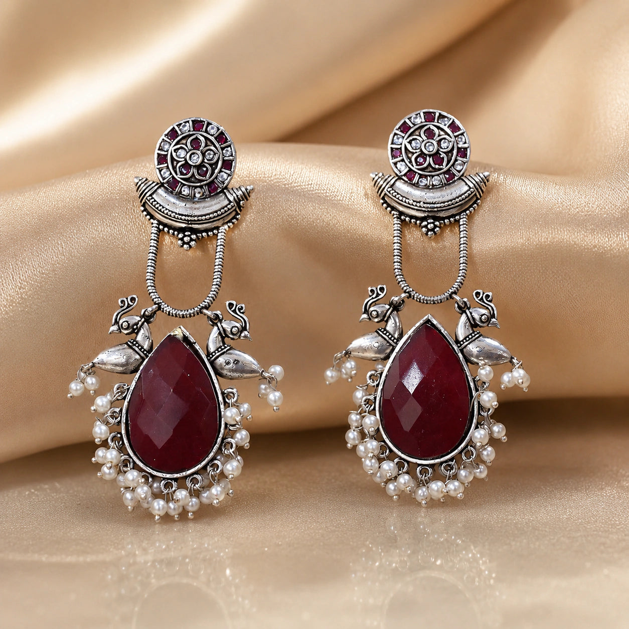 Maroon pearl bird-motif earrings styled in an elegant jewellery flat lay