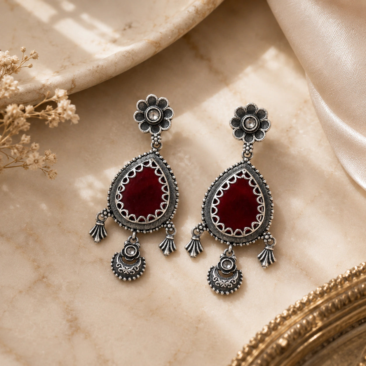 Angled view of German silver maroon teardrop floral dangle earrings