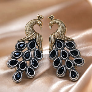 Navy peacock chandelier earrings on a glossy dark reflective jewellery display