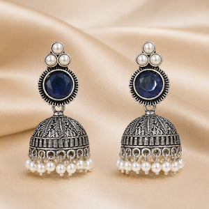 Angled view of German silver navy blue pearl-style dome jhumka earrings