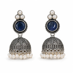 Navy blue pearl-style dome jhumka earrings on a dark jewellery studio display
